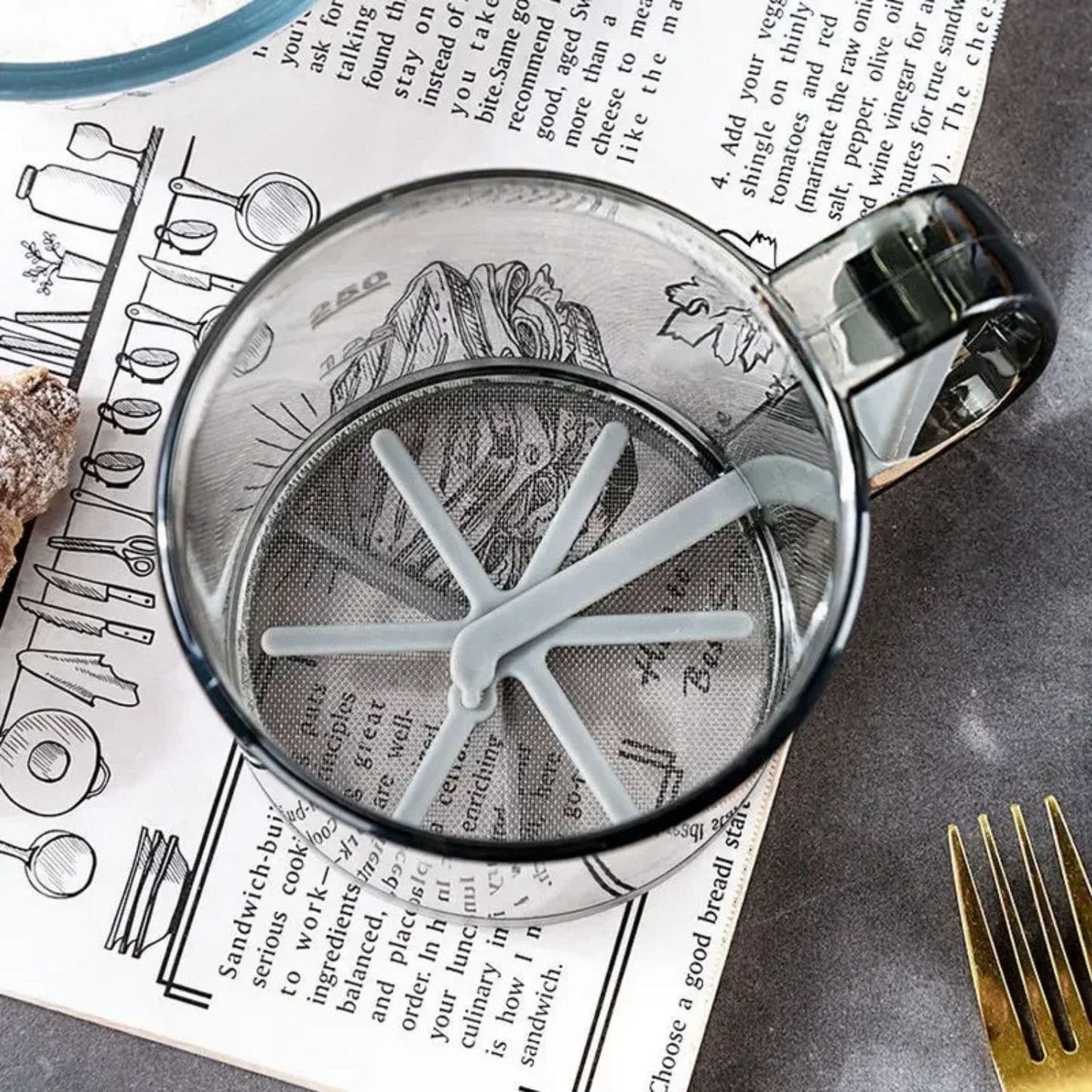 One-handed flour sifter in use, dusting powdered sugar over croissants