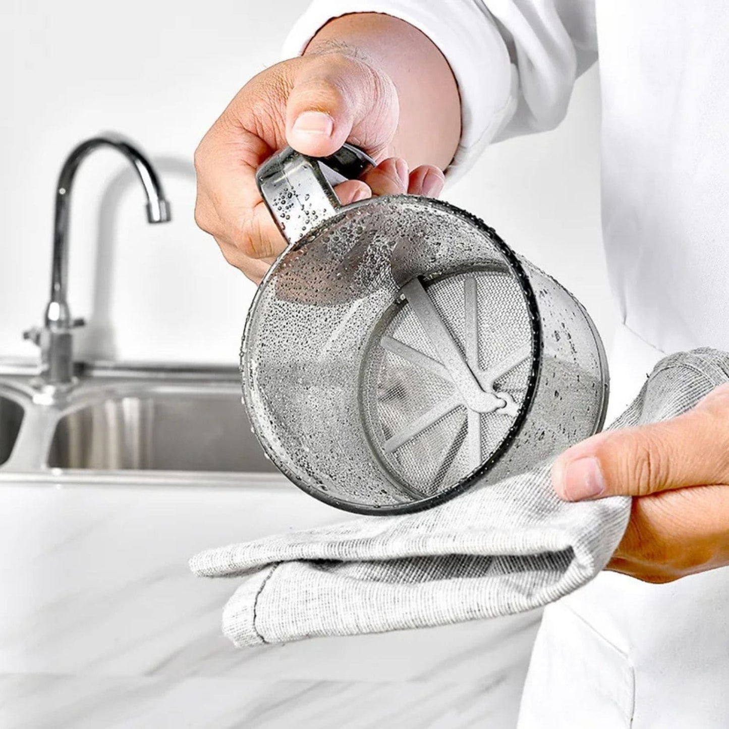 One-handed flour sifter in use, dusting powdered sugar over croissants